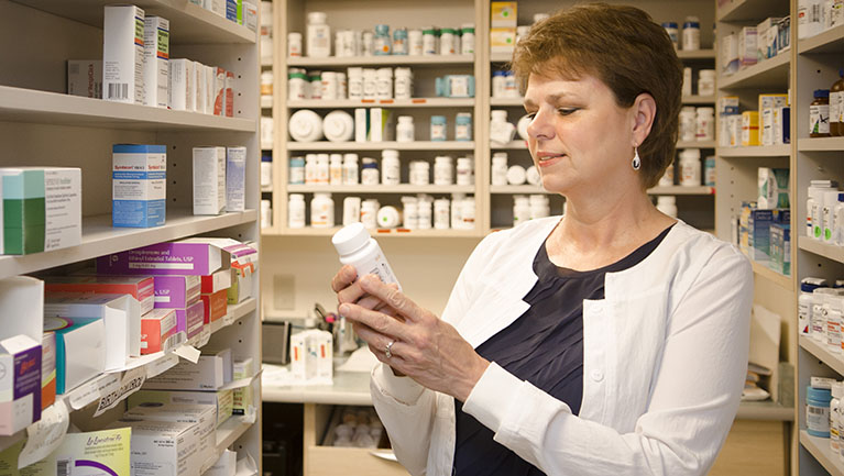 VIMCare pharmacist reading label on bottle of medicine.